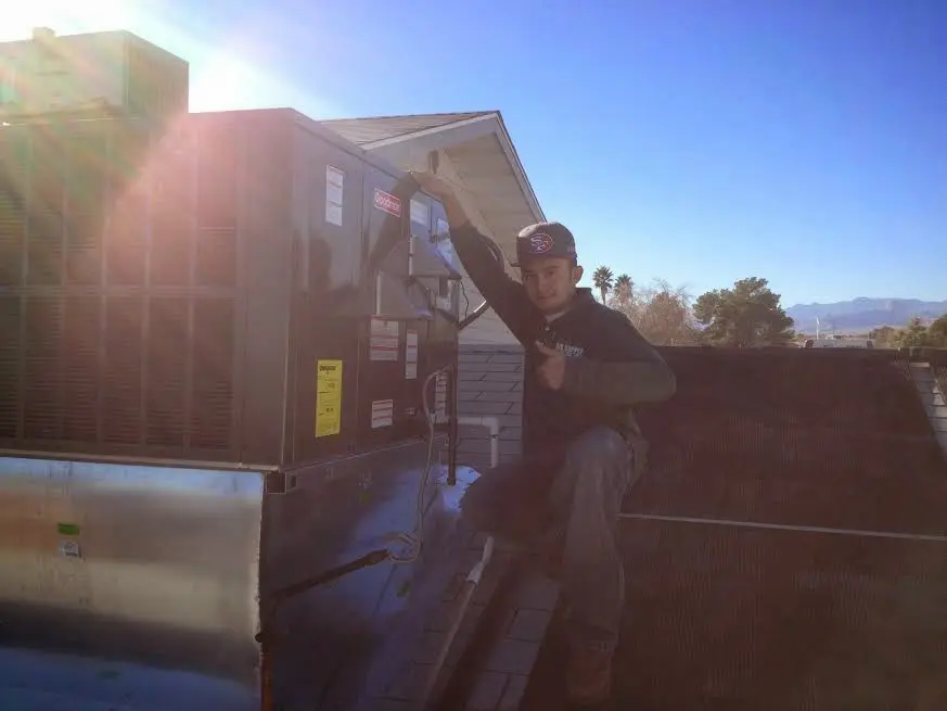 HVAC technician performing Air Duct Repair on a rooftop unit in Hamilton